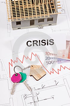 Keys, inscription crisis, euro and downward graphs representing crisis of real estate market. Reduced housing prices. House under