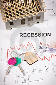 Keys, inscription recession, euro and downward graphs representing crisis of real estate market. Reduced housing prices. House