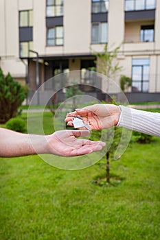 Keys with a keychain in the form of a metal house from a new house or apartment in the hands of a young family. Handing over the