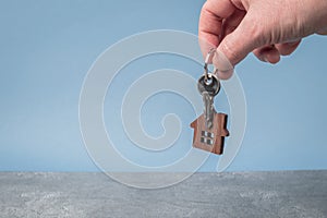 Keys with a model of a wooden house in a man& x27;s hand close-up. Home buying concept.