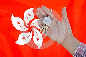 Keys to the apartment in a female hand on background of flag Hong Kong