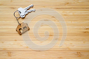Keys to a new house with a house-shaped keyring on a wooden background