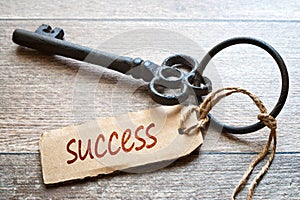 Keys to Success - Concept photo. Old key with paper label on wooden background - Success text.