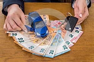Keys and toy car on euro money, female hands