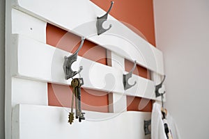 Keys on white wooden hanger on terracotta wall background.