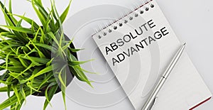 Keyword ABSOLUTE ADVANTAGE - business concept text on a white notebook and pen, green flowers