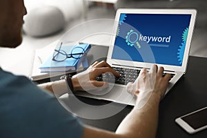 Keywords research. Man working with laptop at table indoors, closeup