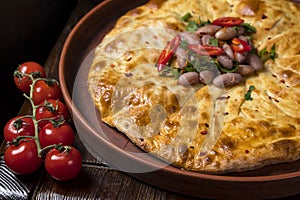 Khachapuri with beans on a wooden background