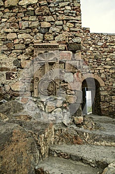 Khachkar at the wall in the courtyard of the medieval fortress Khor Virap and staircase leading to an arched passage with an emerg