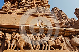 Khajuraho temple reliefs, India. Artworks on walls of 10th century temple with animals, wariors, horseriders