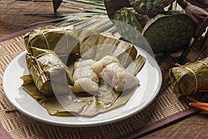 Khao tom mad Thai food style dessert, made from banana and glutinous rice, wrap with banana leaf on wooden table