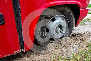 Kharkiv, Ukraine, August, 2019 Bus wheel is bogged down in sand. Red big car stuck in mud. Traffic problem on unpaved road. Dirty