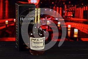 KHARKOV, UKRAINE - FEBRUARY 14, 2021: Hennessy very special cognac bottle on wooden table with red bar interior on background.