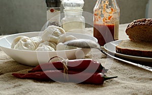 khinkali on the table with ketchup, pepper, bread and chili