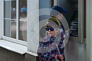 KHMELNITSKY, UKRAINE - JULY 29, 2017: Two brothers near the ATM.