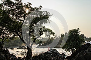 Khone Phapheng Falls at sundown with monk contemplating the mekong , Si Phan Don, Champasak Province, Laos