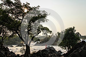 Khone Phapheng Falls at sundown with monk contemplating the mekong , Si Phan Don, Champasak Province, Laos photo