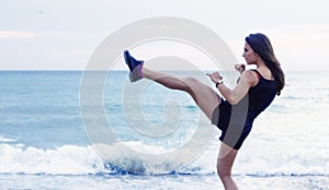 Kick boxing young woman working out on the beach photo