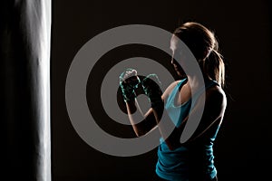 Kick fighter girl in front of a boxing bag