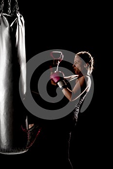 Kick fighter girl punching a boxing bag with her leg