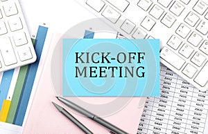 KICK-OFF MEETING text on blue sticker on chart with calculator and keyboard