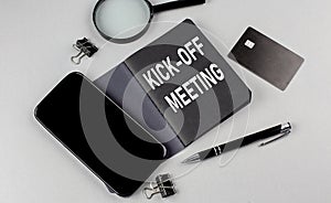 KICK -OFF MEETING text written on black notebook with smartphone, magnifier and credit card