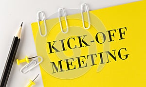 KICK-OFF MEETING word on the yellow paper with office tools on the white background