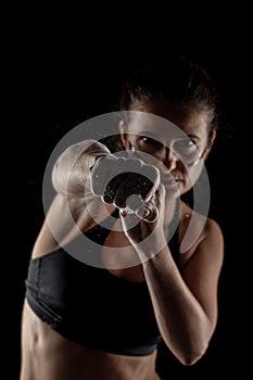 Kickboxer girl with magnesium powder on her hands, punching with dust visible