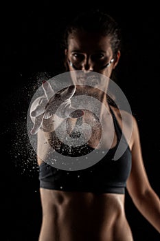 Kickboxer girl with magnesium powder on her hands, punching with dust visible