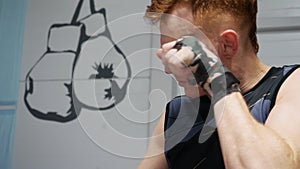 Kickboxer man massaging face before fight training in gym. Boxer man doing warm up exercise at boxing rig in fight club