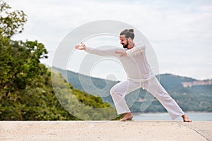 Kickboxer or muay thai fighter Man in white training karate Wushu on mountain