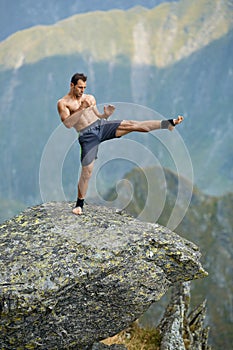 Kickboxer or muay thai fighter training on a mountain cliff