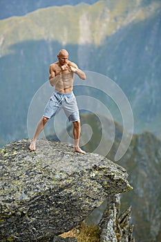 Kickboxer or muay thai fighter training on a mountain cliff