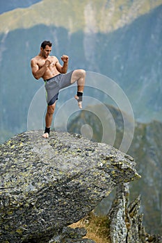 Kickboxer or muay thai fighter training on a mountain cliff