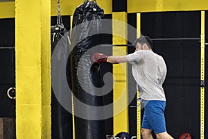 Kickboxing fighter performing punches on punching bag at the gym