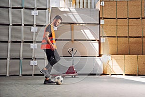 Kicking a soccer ball on the break time. Storage worker is in the warehouse with bunch of products