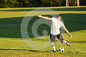 Kicks the ball. Young soccer player have training on the sportive field