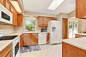 Kicthen in white tones with wooden cabinets and white counter top.