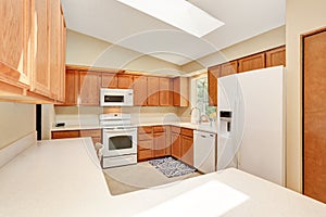 Kicthen in white tones with wooden cabinets and white counter top.