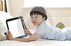 Kid 6-7 year old boy watching cartoon on tablet, Asian child lying in bed showing digital tunch pad, Happy Kid having fun and