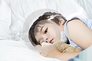 Kid 6-7 year old  lying on bed, Sleepy child waking up the morning in his bed room with morning light, Cute little boy sleeping