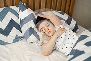 Kid 7 year old lying on bed, Sleepy child waking up the morning in his bed room with morning light, little boy sleeping with his