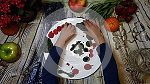 Kid arranging mini colorful pancakes on a white plate. overhead shot