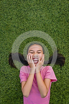 Kid asian girl`s lie leisurely on the Lawn floor and smile looking at