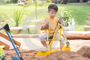 Kid baby boy todler playing construction truck toy diging sand in playground