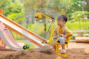 Kid baby boy todler playing construction truck toy diging sand in playground