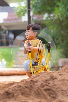 Kid baby boy todler playing construction truck toy diging sand in playground