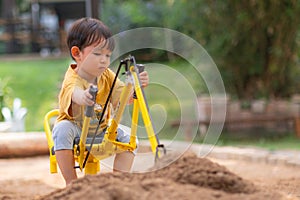 Kid baby boy todler playing construction truck toy diging sand in playground