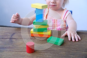 Kid, baby builds towers and buildings from colored wooden figures, the concept of housing construction, mortgage, insurance, happy
