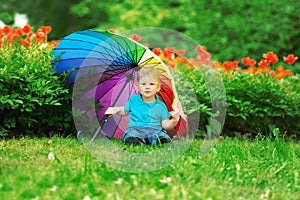 Kid, baby with rainbow umbrella in park. A child on a background